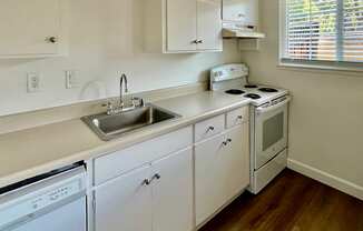 a kitchen with white cabinets and a sink and a stove