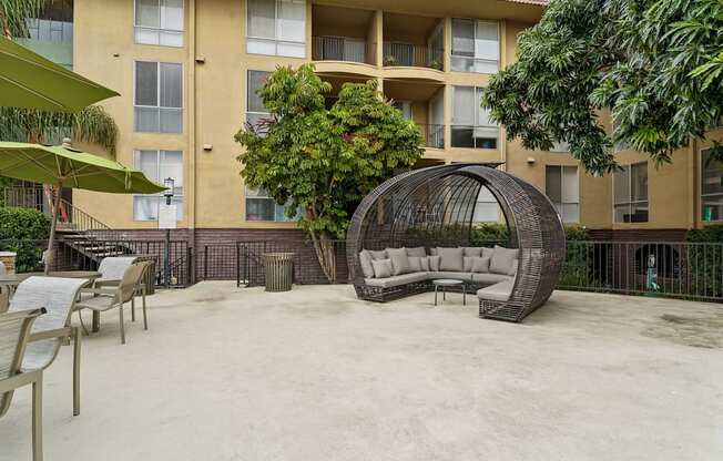A patio with a white couch and a black chair.