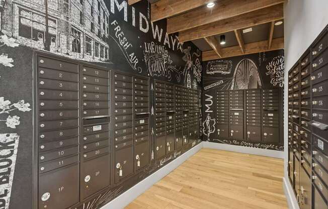A wall of mailboxes with a chalkboard style design on the wall above them.