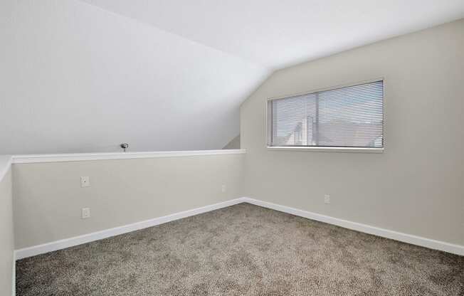 an empty bedroom with carpet and a window