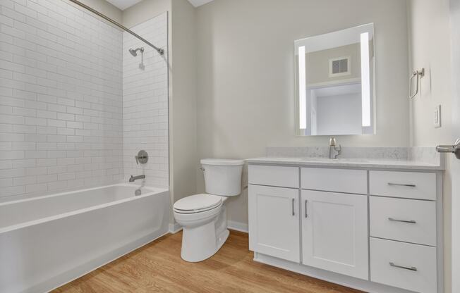 a bathroom with white cabinets and a white bathtub