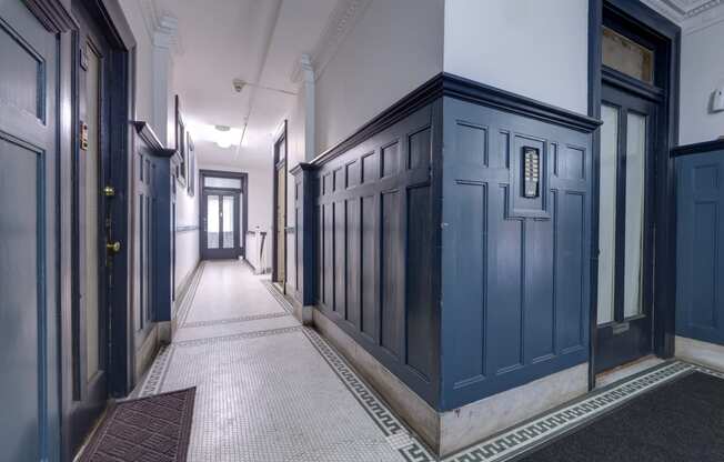 a hallway with blue doors and white walls and a tiled floor