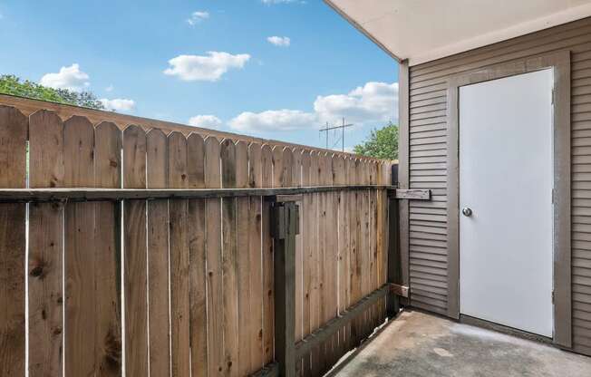 A wooden fence with a white door and a grey wall.