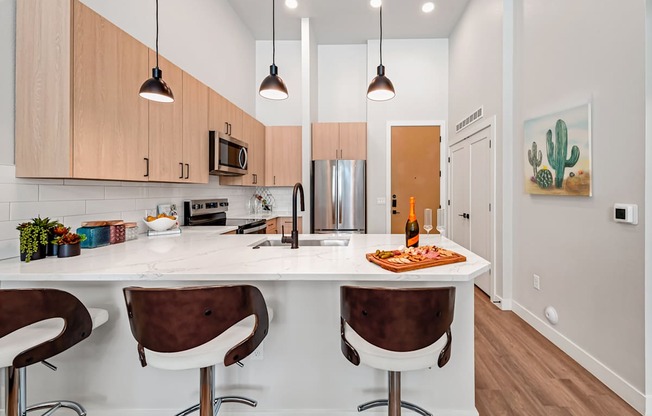 A kitchen with a white counter top and brown chairs.