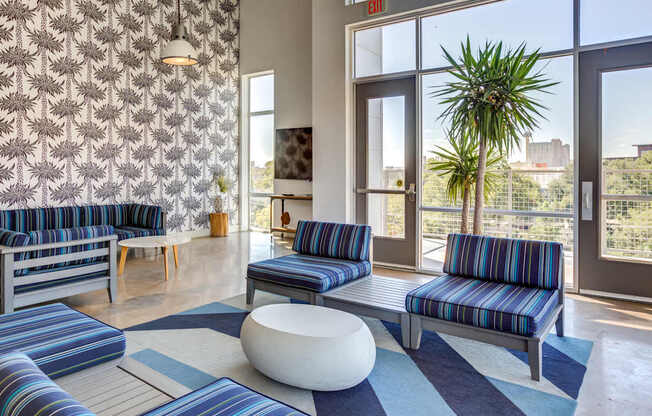 A room with blue and white striped couches and a white ottoman.