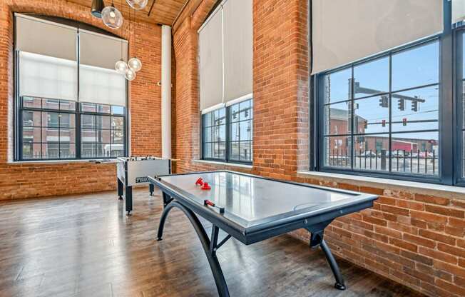 two ping pong tables in an empty game room with brick walls and large windows