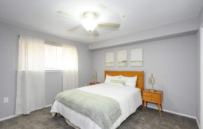A bedroom with a bed, nightstand, and a ceiling fan.