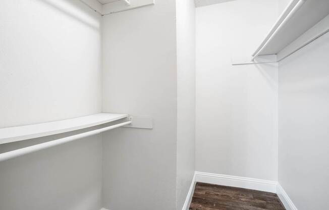 A white closet with a shelf and a wooden floor.