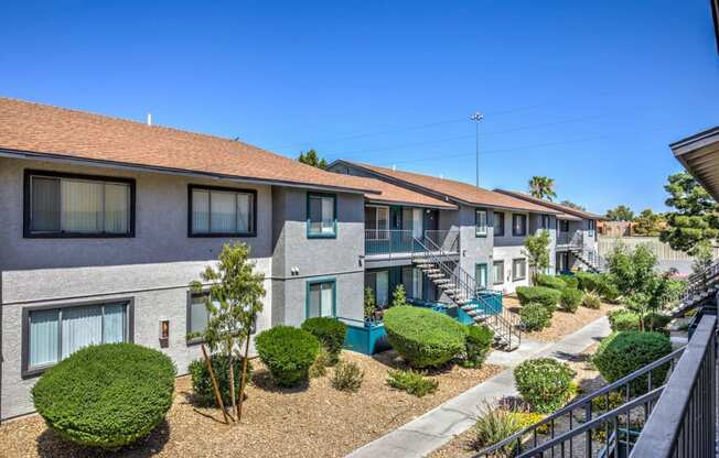 a row of townhomes with balconies and shrubs and stairs