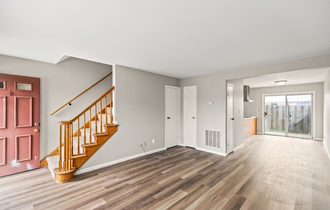 A room with a wooden floor and a red door.