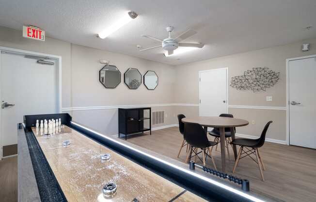 a recreation room with a shuffleboard table and chairs