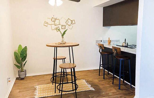 a living room with a bar with stools and a ceiling fan