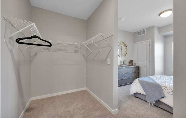 A bedroom with a bed, dresser, and a hanger on the wall.