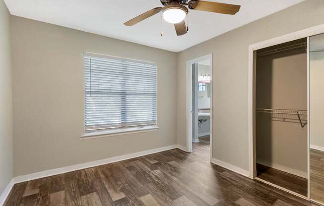 Model bedroom with sliding door closet, hard wood vinyl flooring, and ceiling fan at Mirage on Kernan in Jacksonville, Florida.