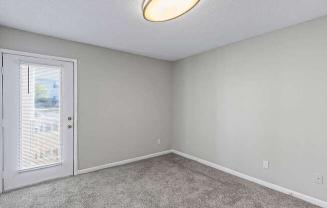A room with a carpeted floor and a door leading outside.