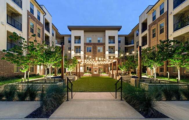 an exterior view of an apartment complex with a green courtyard