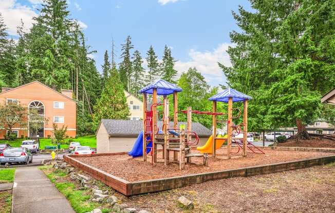 A playground with a red swing set and a blue canopy.
