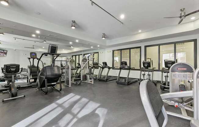 A gym with a variety of equipment including treadmills, weights, and exercise machines at Prairie Crossing, Texas 75244