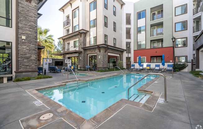 A swimming pool surrounded by buildings and chairs.