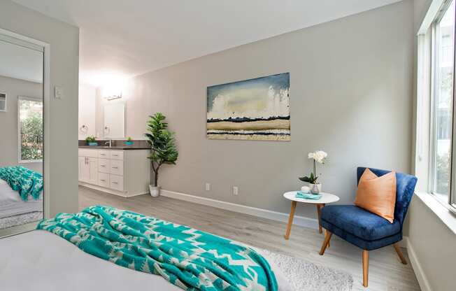 Bedroom with wood-inspired floors, mirrored closet doors and a vanity area on the left