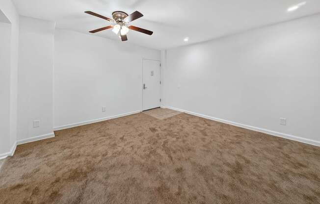 A room with a ceiling fan and carpeted floor.