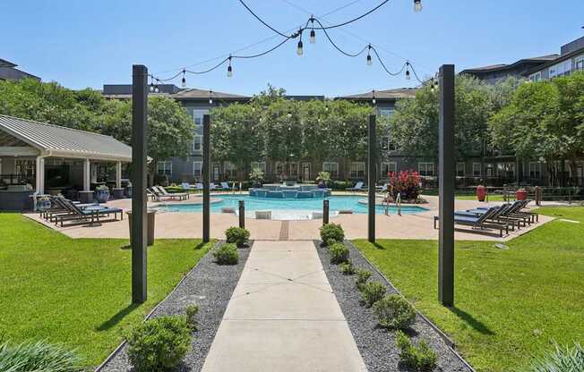 A pool surrounded by a grassy area and trees.