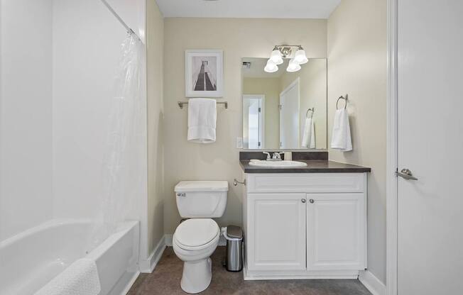 A white toilet sits in a bathroom next to a white bathtub.