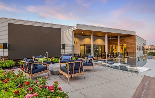 a patio with chairs and a pool in front of a building