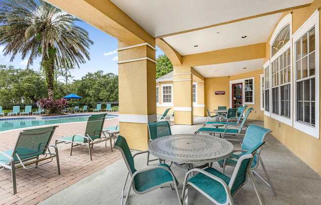 A patio with a table and chairs overlooking a pool.