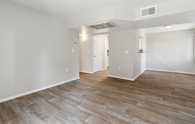 the living room and dining room in a new home with white walls and wood floors