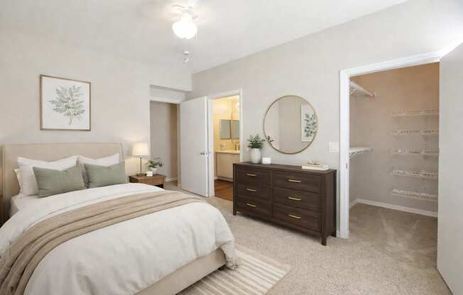 A bedroom with a large bed and a dresser with a mirror.