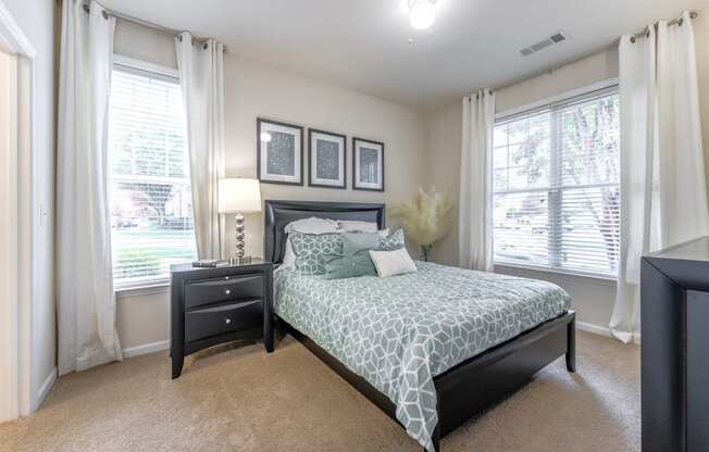 A bedroom with a bed, nightstand, and window.