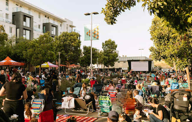 A large crowd of people are gathered in a park for an outdoor event.