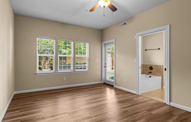 Little Tuscany Apartments & Townhomes - Bedroom with Bathroom, vinyl wood plank flooring, white woodwork, ceiling fan, natural light