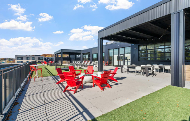 a patio with red chairs and tables outside of a building