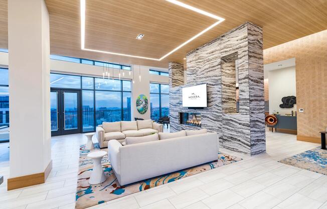 Resident lounge with city views, sculptural lighting, and tailored seating centered around a fireplace for connection, conversation, and relaxed downtime.