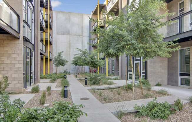 a courtyard with trees and plants in front of a building
