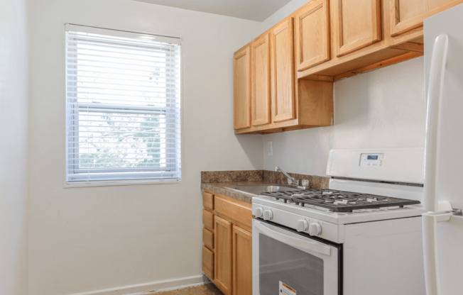 A kitchen with a white stove and wooden cabinets.