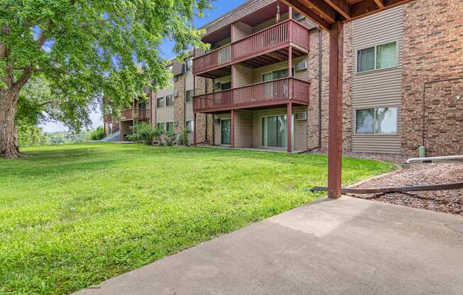 A grassy area in front of a brick building with a tree.