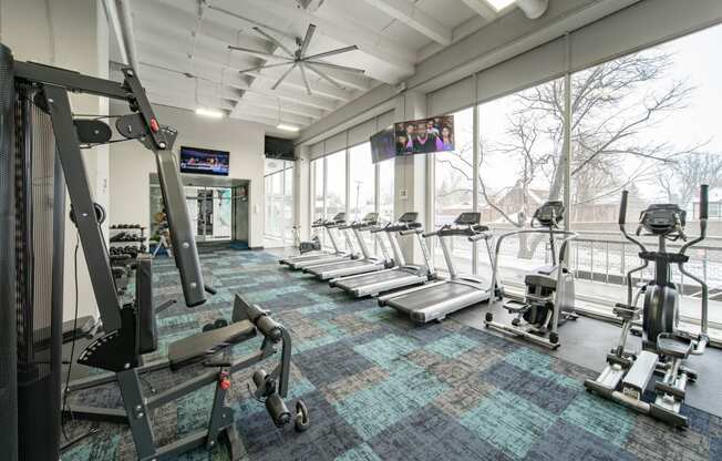 a gym with treadmills and other exercise equipment and a large window