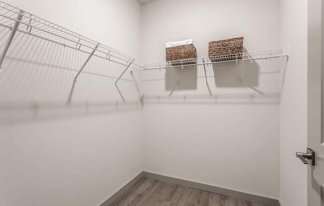 A white room with a wire shelving unit and two baskets on the shelf.