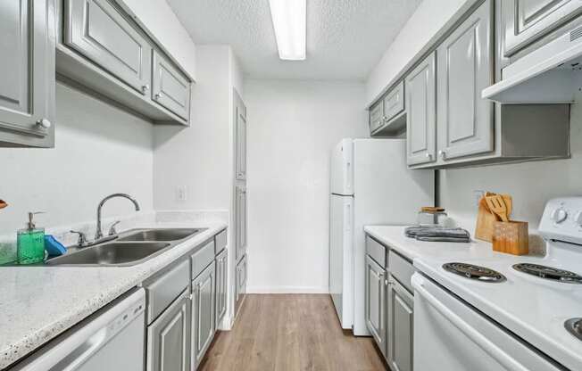 A kitchen with white appliances and grey cabinets.