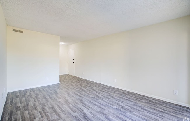 an empty living room with wood floors and white walls