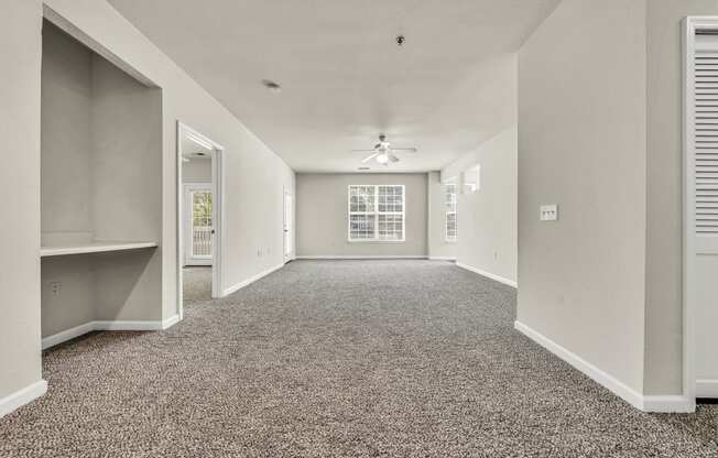 an empty living room with carpet and a ceiling fan