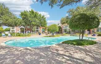 A swimming pool surrounded by trees and a brick patio.