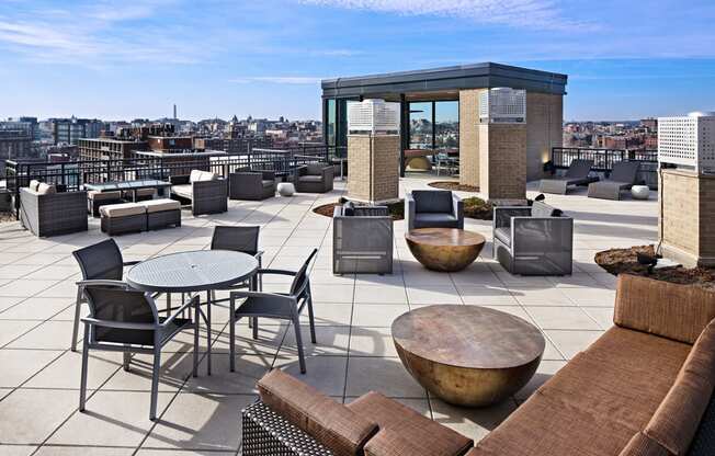 a rooftop terrace with couches tables and chairs and views of the city