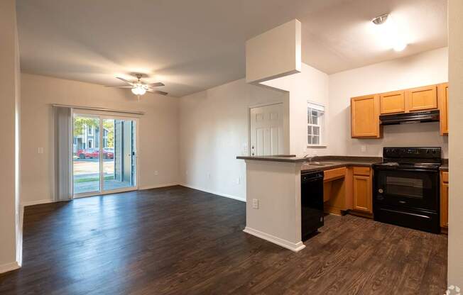 A kitchen with wooden floors and black appliances.