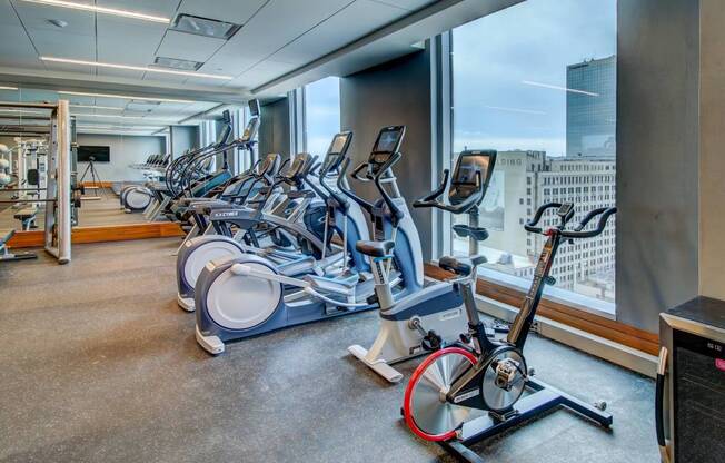 A gym with exercise bikes and a view of the city.