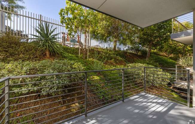 a balcony with a metal railing and a green garden