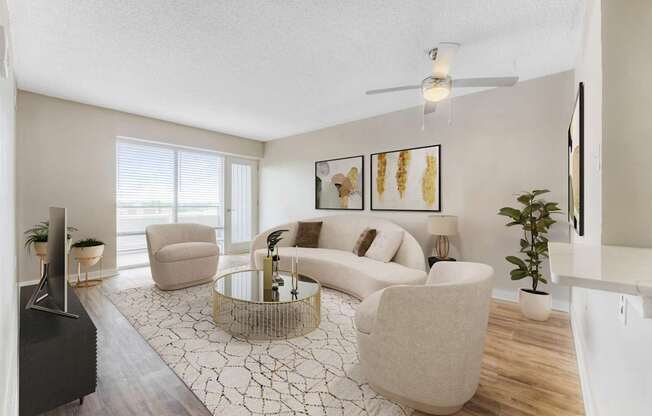 A living room with a white sofa, a glass coffee table, and a TV.at Iris Luxury Apartments, Memphis, TN